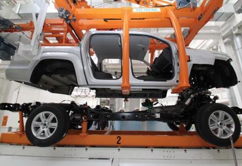 Chasis de camioneta avanzando sobre un transportador naranja