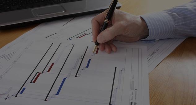 Mano trazando un diagrama de Gantt sobre un cronograma impreso