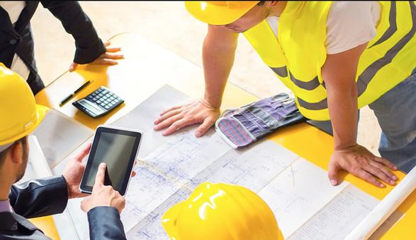 Equipo con cascos revisando planos y una tablet