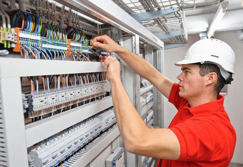 Técnico cableando un tablero de automatización con PLC