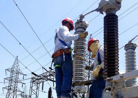 Técnicos trabajando en una subestación eléctrica de alta tensión