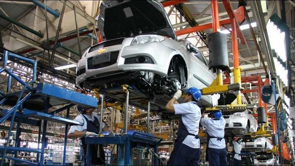Operarios bajo un vehículo en una línea con transportadores